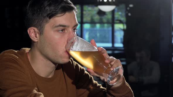 Attractive Man Sipping Delicious Beer From His Glass, Relaxing at the Bar