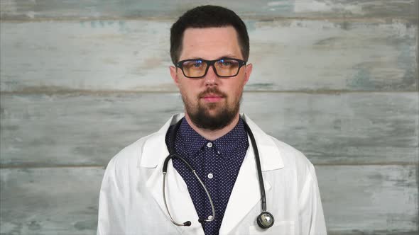 Portrait of Adult Male Doctor with Stethoscope in White Coat and Glasses.