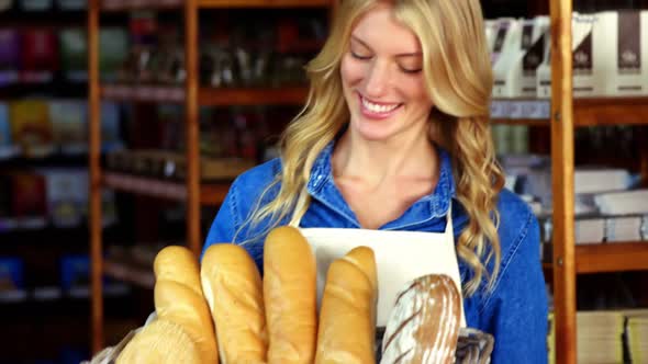 Smiling woman holding a basket of baguettes in organic shop