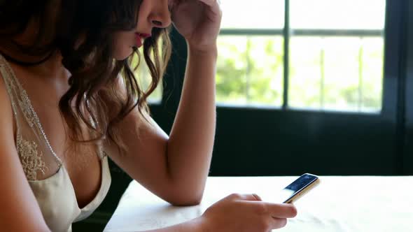 Sad woman using mobile phone at table 4k