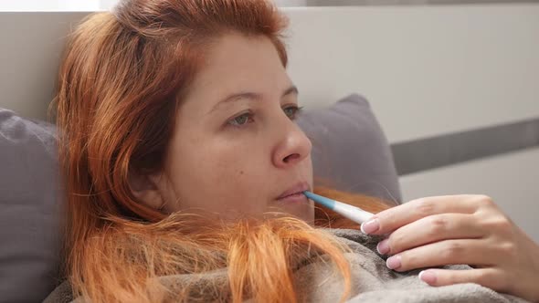 Slow motion of female measuring body temperature while in bed  1920X1080 HD footage - Ill redhead wo