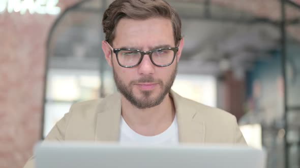 Thumbs Down By Young Man with Laptop