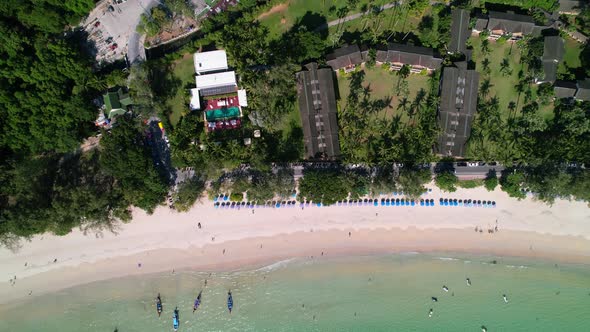 top down view of a blue umbrellas and resort on a white sand tropical Karon beach with turquoise blu