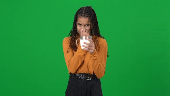 Portrait of Dissatisfied Teen Girl with Disgust Facial Expression Holding Milk in Cup Closing Nose