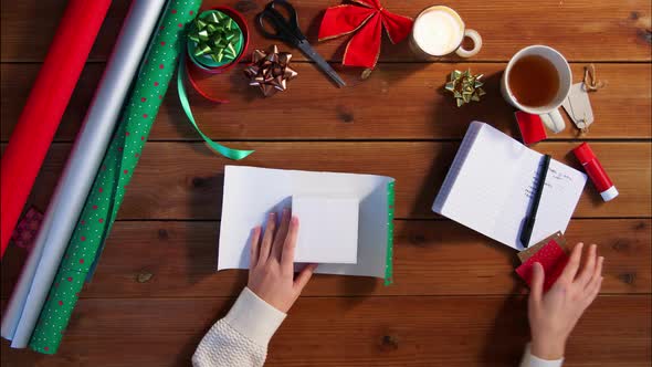 Hands Wrapping Christmas Gift and Writing Note