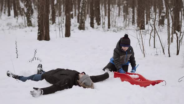 Dad and Son are Playing in Winter Snowy Forest