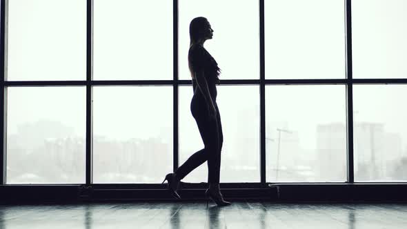 Silhouette of a Slim Girl Walking on the Background of a Large Window