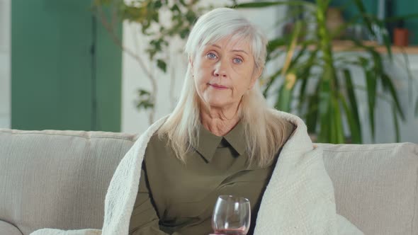 Tired Depressed Elderly Woman Sitting on the Sofa With a Glass Of Wine