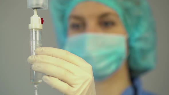 Female Nurse Checking Dropper With Medication, Rendering First Aid to Patient