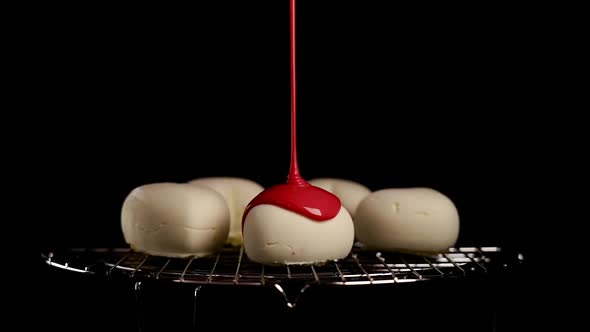 Pouring Sweet Red Icing Onto Small Cake on Cooling Tray