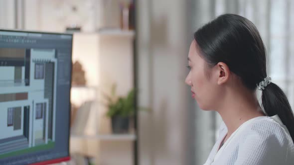 Close Up Of Asian Woman Engineer Rotate 3D House While Working On A Desktop At Home