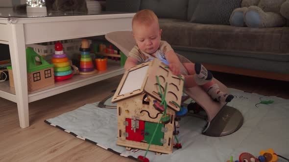 Adorable Baby Sitting in Infant Bouncer 10 Month Old Caucasian Kid Playing with Wooden Busy House