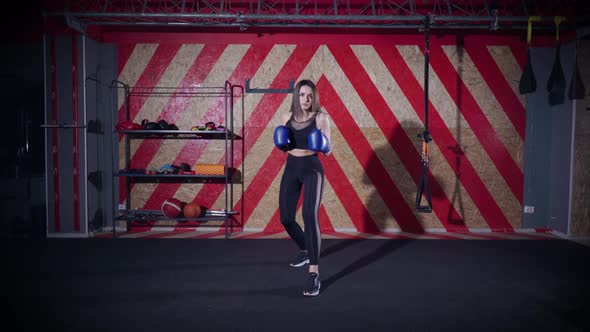 Young Woman in Boxing Gloves Prepares for a Fight and Makes Several Blows to the Camera