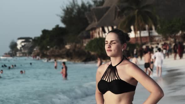 Young Beautiful Woman Stands on Exotic Beach and Looks Into the Distance Sunset