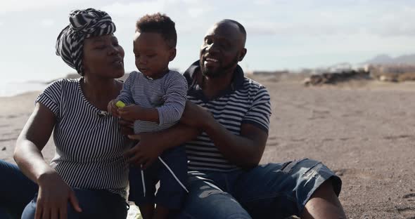 African child having fun with mother and father on the beach - Black family enjoy summer time