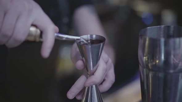  Bartender Hand Pouring Drink From Measuring Cup Into a Metal Shaker