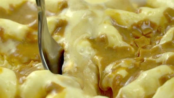 macro shot, a spoon is lowered into the dessert, vanilla ice cream sprinkled