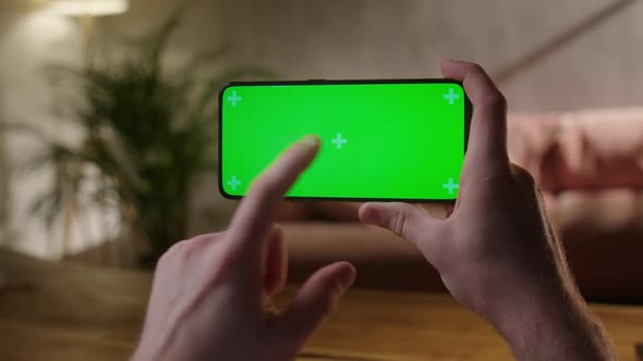 Handheld Camera Back View of Man at Phone with Green Screen for Copy Space