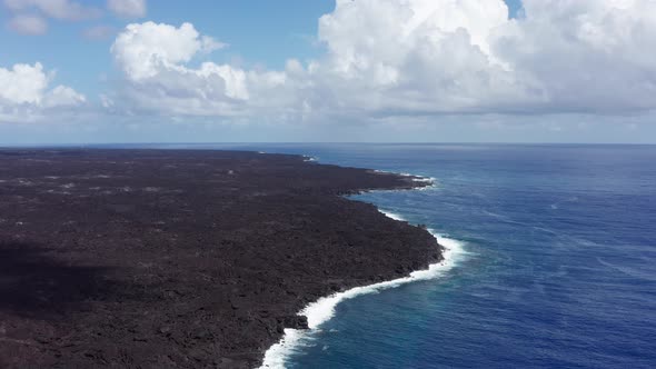 Aerial panning shot of a freshly dried lava flow extending into the ocean on the Big Island of Hawai