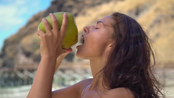 Close Up of Charming Young Woman Drinking Fresh Coconut Juice While Standing on Sunny Tropical Beach