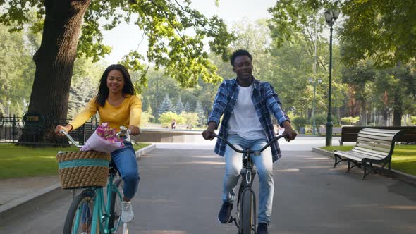 Young Active African American Couple in Love Spending Date Outdoors Riding Bicycles and Talking