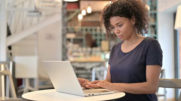 Professional Young African Woman Using Laptop in Cafe