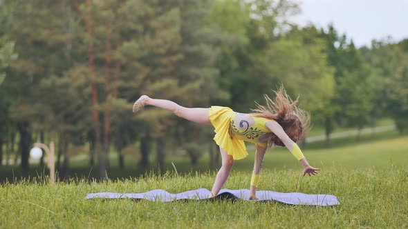 A Little Girl Performs the Elements of Rhythmic Gymnastics in the Park