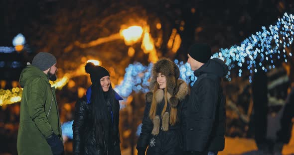 Young and Beautiful Friends Are Standing on a Winter Street and Laughing. Everything Is Decorated