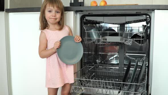 Girl Smiles Loads Dishes in Dishwasher