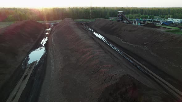 Piles of Lignin Stored in an Open Warehouse in a Wooded Area