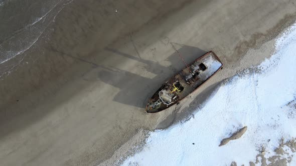 Aerial Top View of Old Wrecked Fishing Ships Drowned at the Sea Shore in Snowy Winter Season
