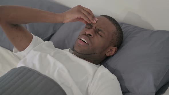 African Man Having Headache While Sleeping in Bed Close Up