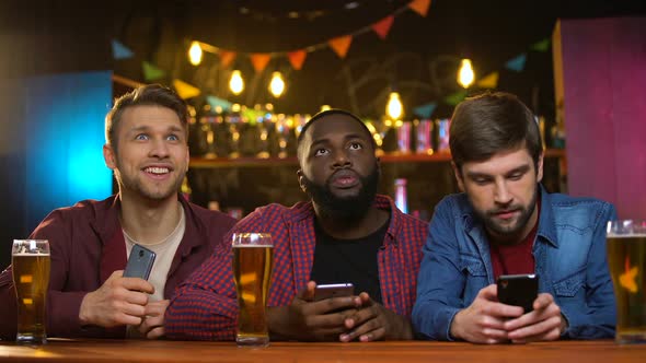 Multiethnic Male Friends Watching Football Match in Pub, Upset With Team Losing