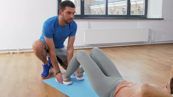 Woman with Personal Trainer Doing Sit Ups at Home