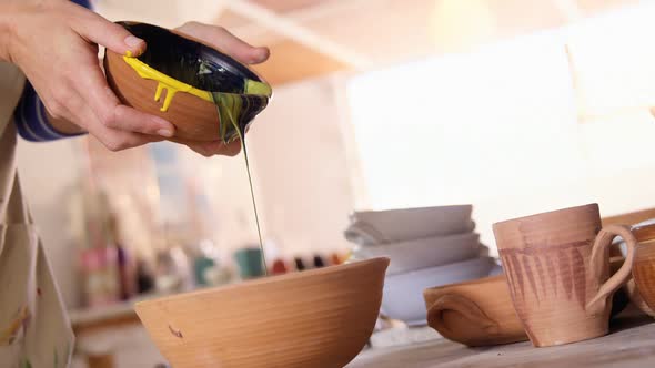 Female potter pouring paint into bowl