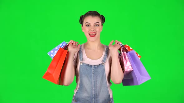 Girl with Shopping Packages of Different Colors Joyfully Dance on a Green Screen