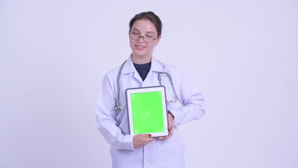 Happy Young Beautiful Woman Doctor Thinking While Showing Digital Tablet