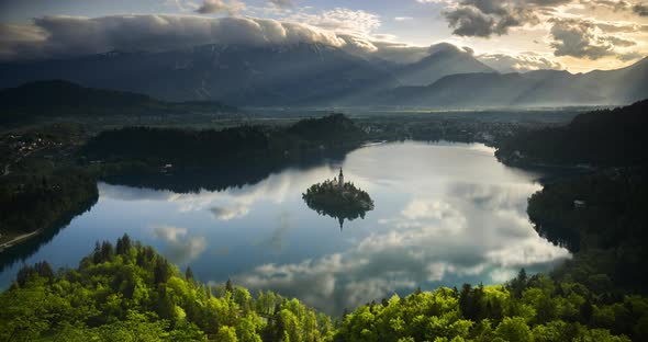 Timelapse of mountain landscape at sunrise with sunlight hitting Lake Bled island in Slovenia