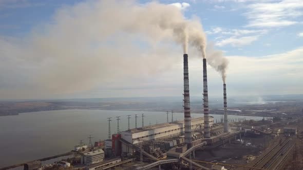 Aerial view of high chimney pipes with grey smoke from coal power plant. Production of electricity