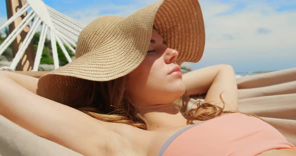 Front view of Caucasian woman relaxing in a hammock at beach 4k