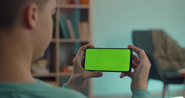 Man Holding Mobile in Horizontal Position with Green Screen