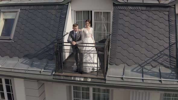 Caucasian Newlyweds Bride Embracing Groom on Balcony in Hotel Room Aerial View