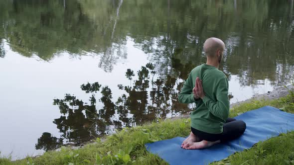 a Man with His Hands Behind His Back is Engaged in Spiritual Practice on the Banks of a River or