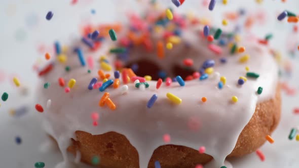 Sprinkling candy chocolate on frosted doughnut. Slow Motion.