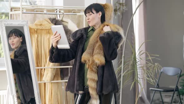 Positive Female Blogger Using Tablet Streaming Online in Fashion Shop