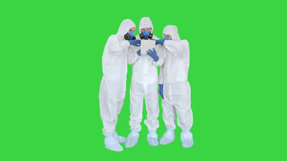 Doctors or Scientists Wearing Hazmat Suits Working Together on Digital Tablet on a Green Screen