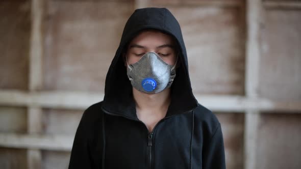 A teenager in a respirator looks down