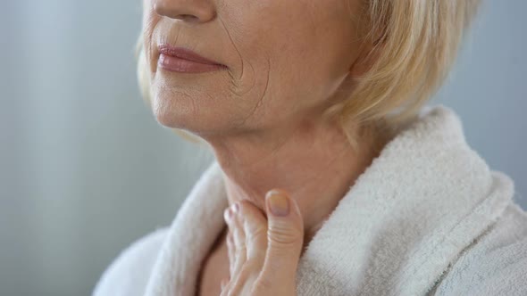 Elderly Female Touching Her Face and Neck, Applying Cream, Femininity Beauty