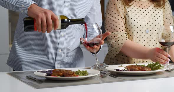 Young Romantic Couple Celebrating with Glasses of Red Wine and Tasty Dinner