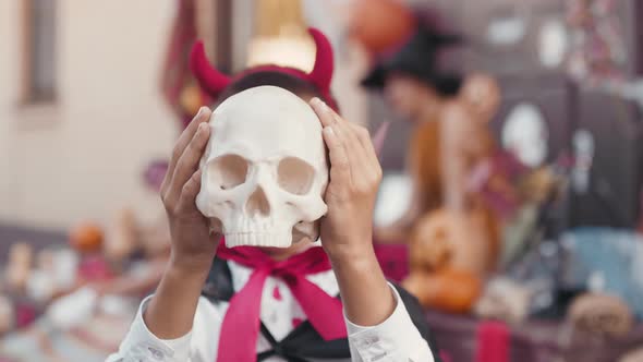 Cute Boy in Halloween Costume Holding Skull